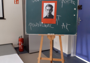 Widok na tablicę z portretem K. K. Baczyńskiego, w tle zdjęcie poety z mamą.